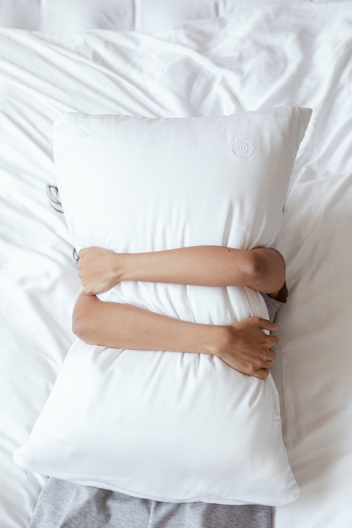 Female model hugging white bamboo pillowcase and pillow